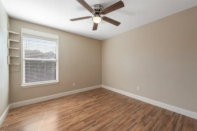 a view of an empty room with window and a chandelier fan