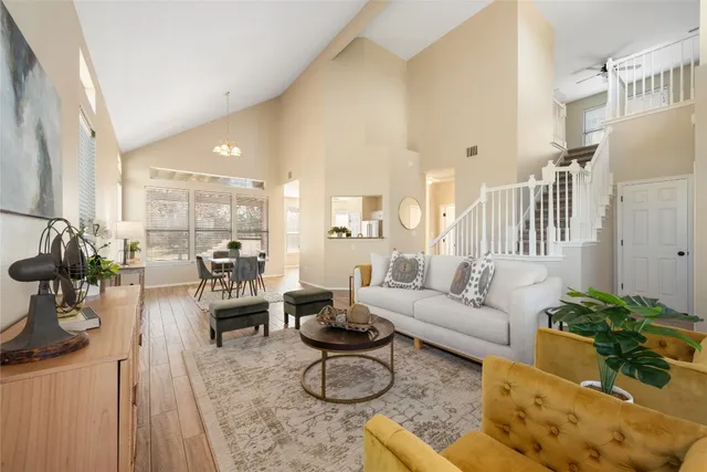 a living room with furniture large window and wooden floor