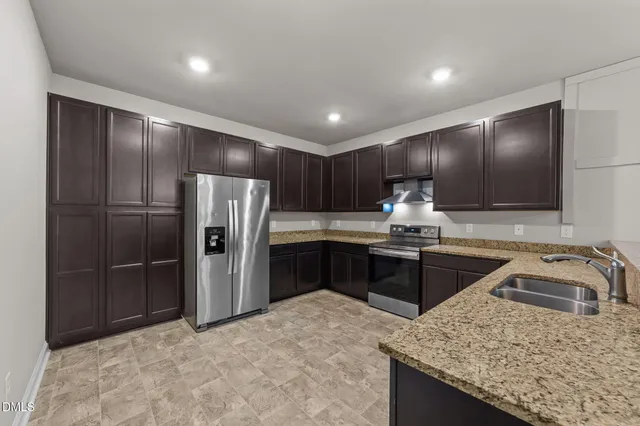 a kitchen with granite countertop a refrigerator and a sink