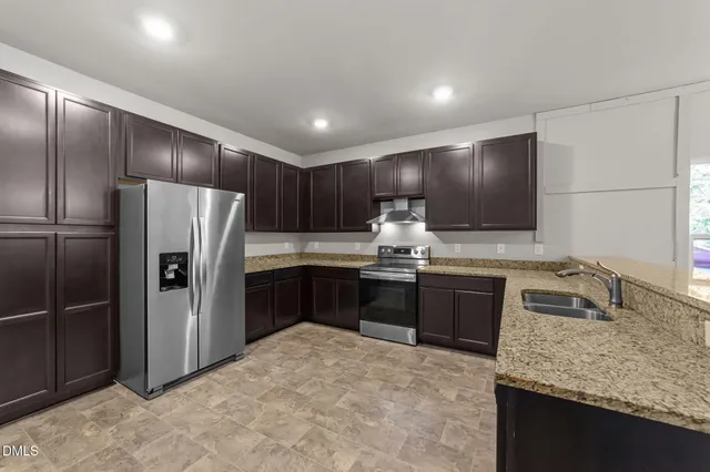 a kitchen with granite countertop a refrigerator and a sink
