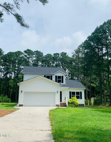 a front view of a house with a garden and trees