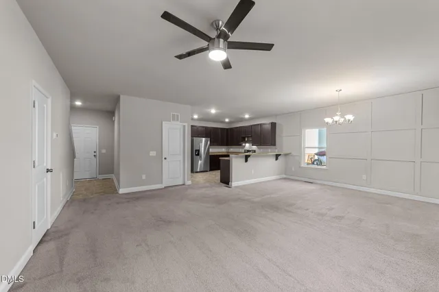 a view of a livingroom with a ceiling fan and kitchen view