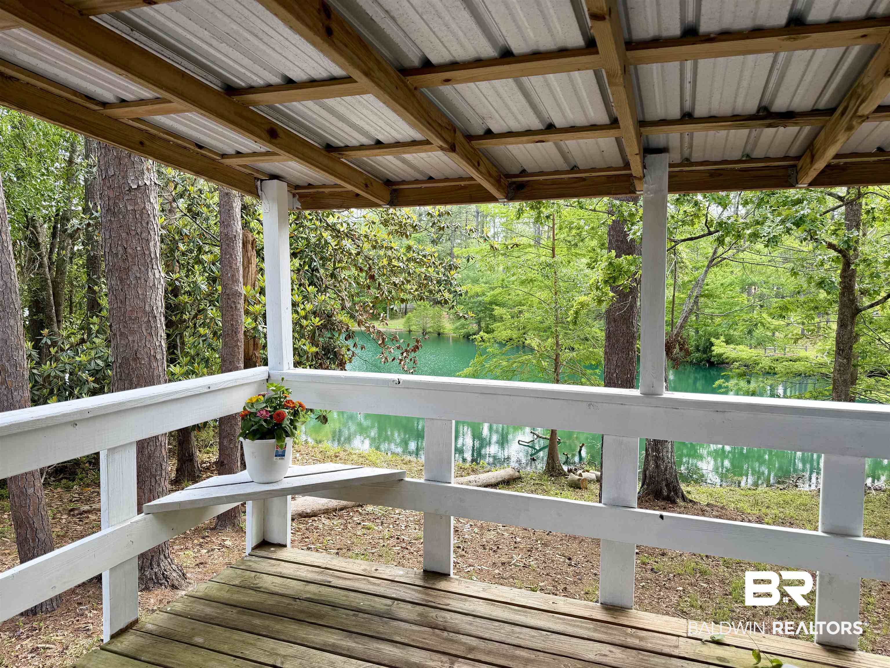 762 Buddy Lake Road Brewton, AL 36426 - Photo 16 of 20 Covered porch featuring a wood-finish deck, white railing, and a metal roof supported by exposed wood beams