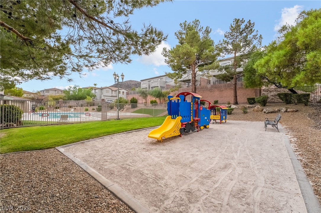 224 Positive Point Street Henderson, NV 89012 - Photo 43 of 44 A community playground area sits adjacent to a fenced swimming pool surrounded by mature trees.
