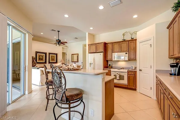 a kitchen with stainless steel appliances granite countertop a refrigerator a stove top oven a sink dishwasher and white cabinets with wooden floor