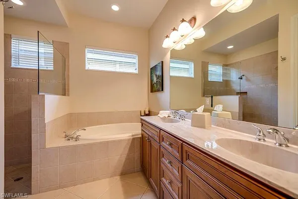 a bathroom with a tub a sink and mirror
