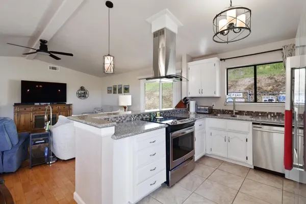 a kitchen with granite countertop stainless steel appliances a counter space and a view of living room