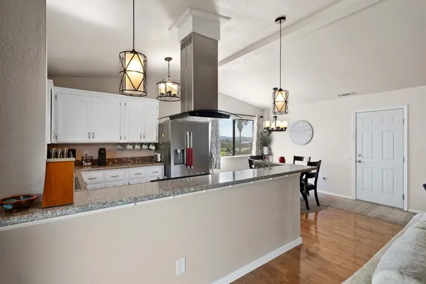 a living room with kitchen island stainless steel appliances furniture a flat screen tv and a window