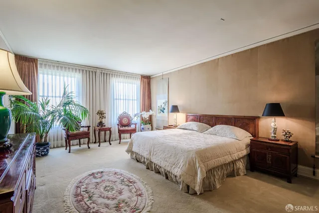 a spacious bedroom with a bed a chandelier and a window