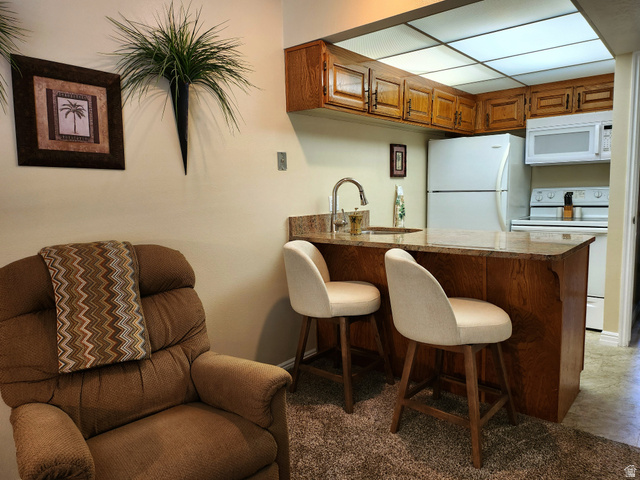860 South Village Road, Unit Z10 St. George, UT 84770 - Photo 3 of 18 Kitchen featuring white appliances, wood finish cabinets, a peninsula, a breakfast bar area, and light countertops