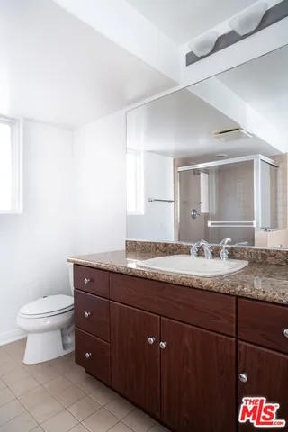 a bathroom with a granite countertop sink a toilet and a mirror