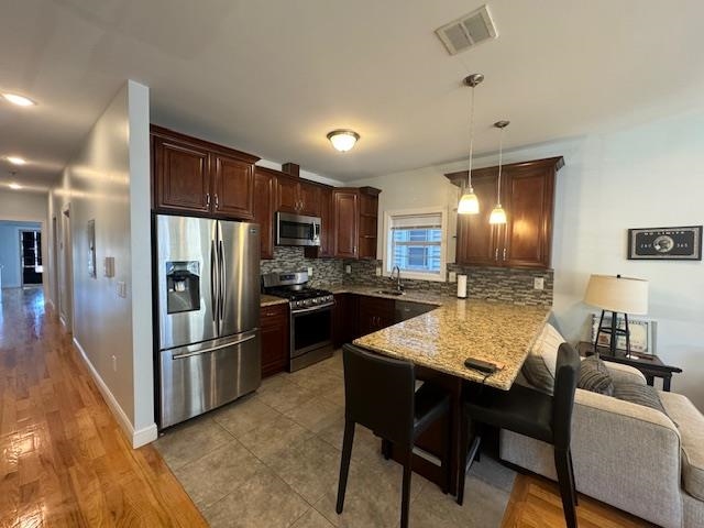 a kitchen with stainless steel appliances kitchen island granite countertop a refrigerator a stove a microwave oven a sink with island and chairs