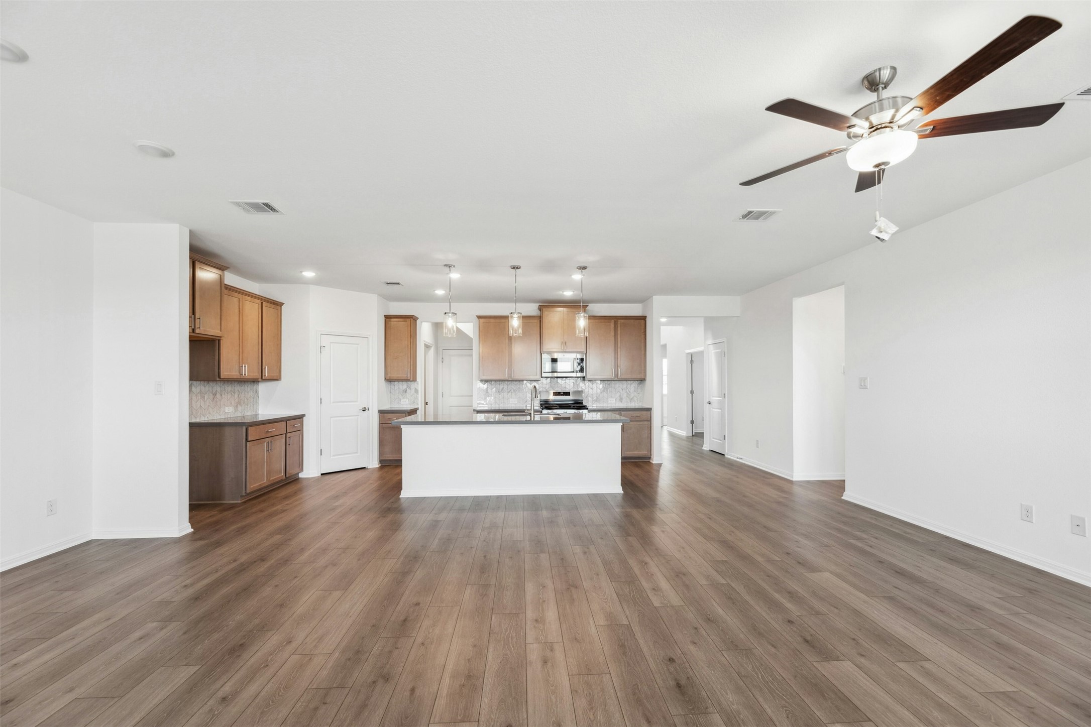 2001 Wynn Road Hutto, TX 78634 - Photo 39 of 39 A generous open floorplan connects a well-appointed kitchen to ample living space, featuring rich hardwood flooring and recessed lighting.