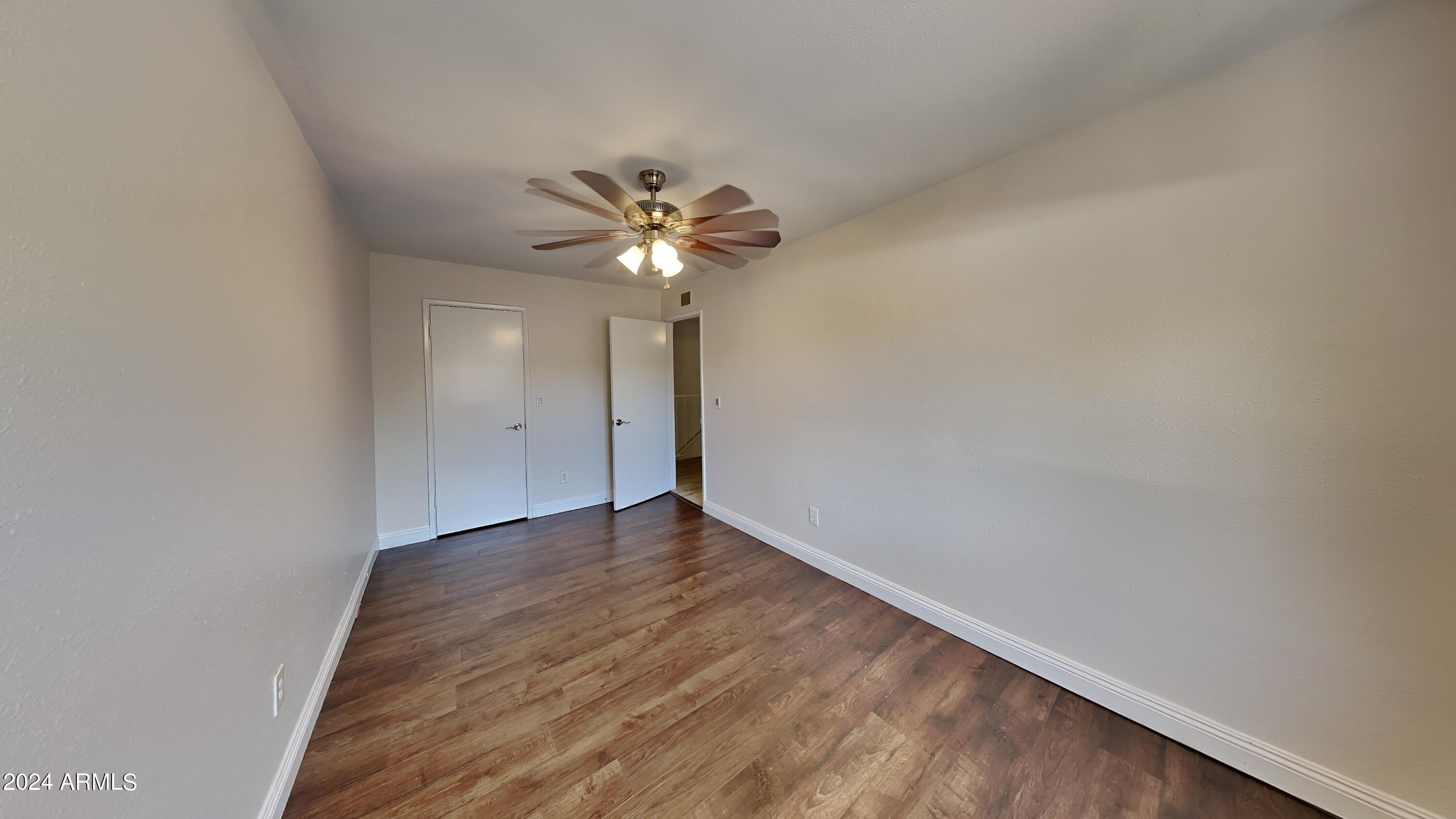 1051 South Dobson Road, Unit 166 Mesa, AZ 85202 - Photo 1 of 13 an empty room with a chandelier fan and wooden floor