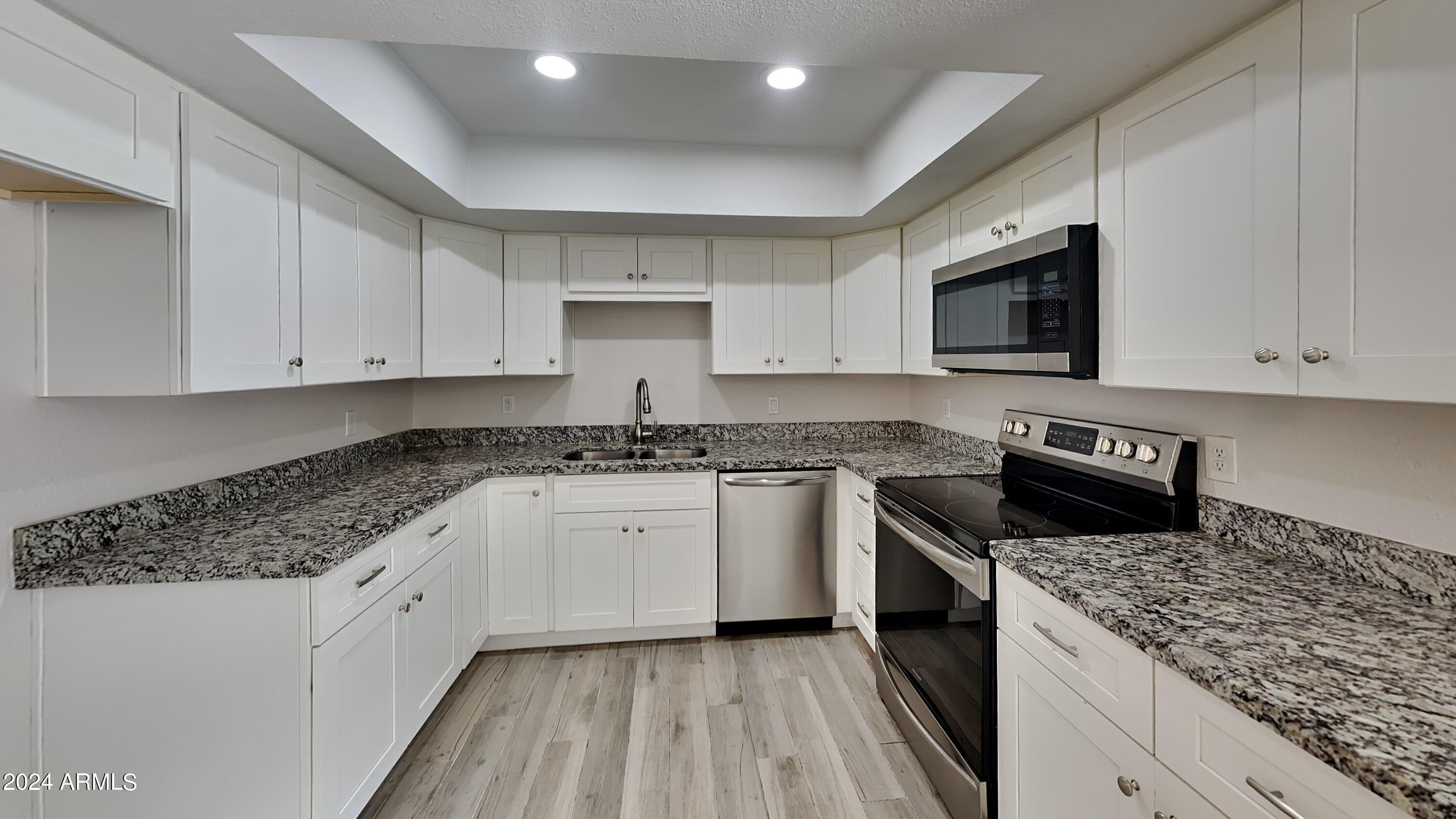 1051 South Dobson Road, Unit 166 Mesa, AZ 85202 - Photo 8 of 13 a kitchen with granite countertop white cabinets sink and stainless steel appliances