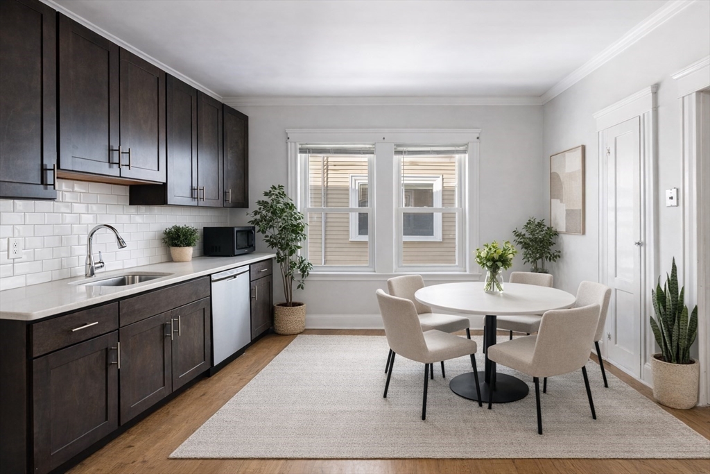193 Florence Street, Unit 2R Boston, MA 02131 - Photo 2 of 14 a kitchen with granite countertop a table chairs sink and cabinets