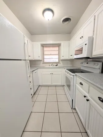 a kitchen with white cabinets appliances and a sink