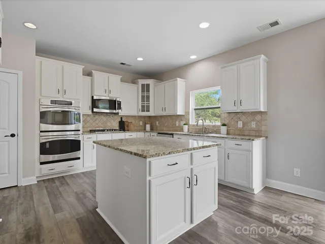 a kitchen with kitchen island granite countertop white cabinets and white appliances