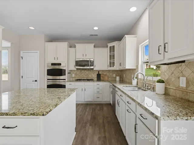 a large kitchen with stainless steel appliances granite countertop a lot of counter space and wooden cabinets