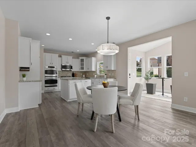 a view of a dining room and livingroom with furniture wooden floor a chandelier