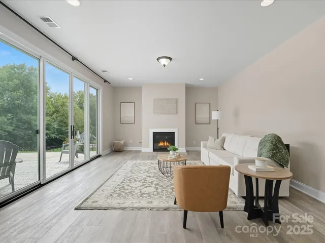a living room with furniture a fireplace and a floor to ceiling window