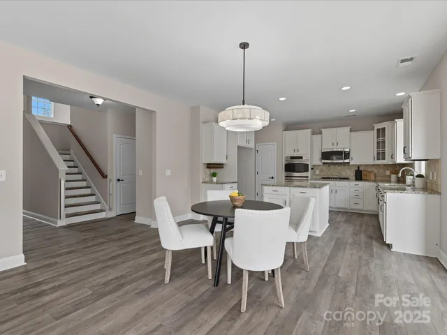 a view of a dining room and livingroom with furniture wooden floor a chandelier