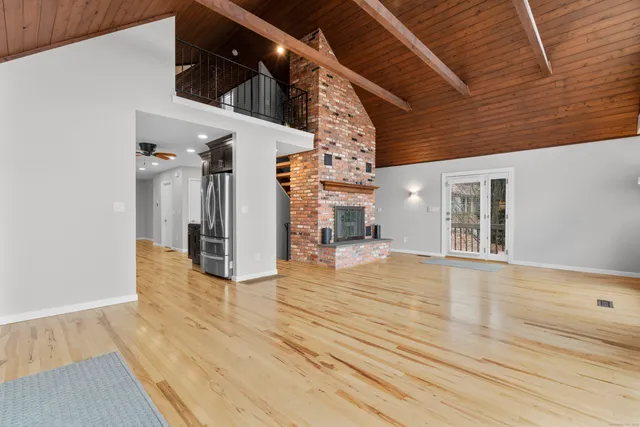 a view of an empty room with wooden floor and a fireplace