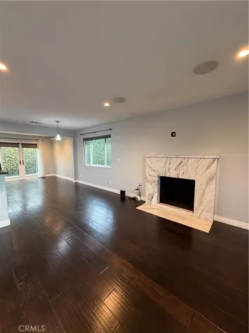 an empty room with wooden floor fireplace and windows