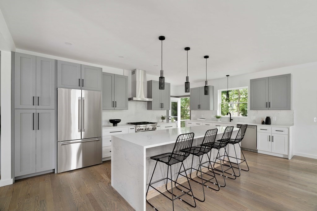 51 Eliot Road Arlington, MA 02474 - Photo 24 of 42 a kitchen with stainless steel appliances a dining table chairs a refrigerator and cabinets