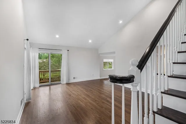 a view of an empty room with wooden floor and stairs