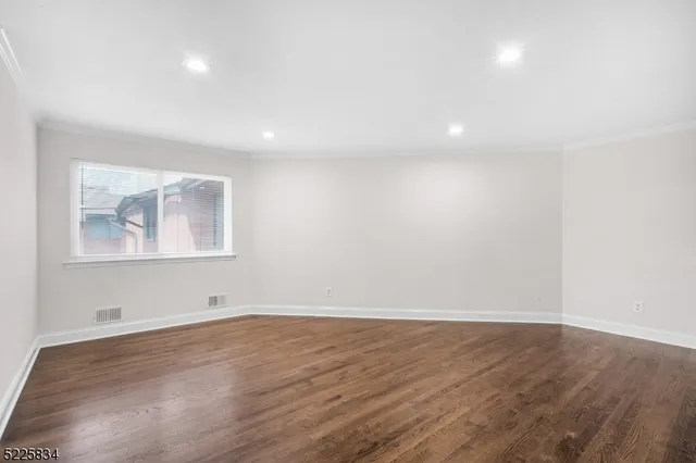 an empty room with wooden floor and window