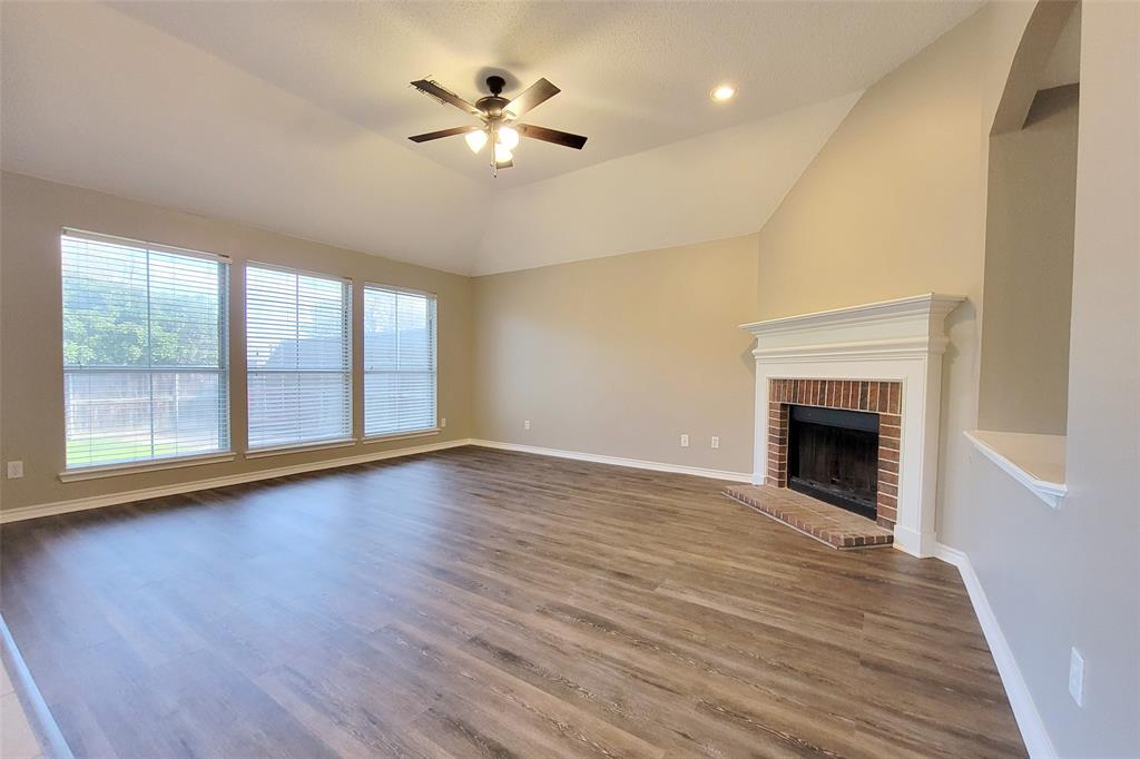 1604 Knoll Ridge Circle Corinth, TX 76210 - Photo 20 of 37 Spacious living area featuring vaulted ceilings, wood-finish flooring, a brick fireplace with a substantial white mantel, recessed lighting, and a ceiling fan