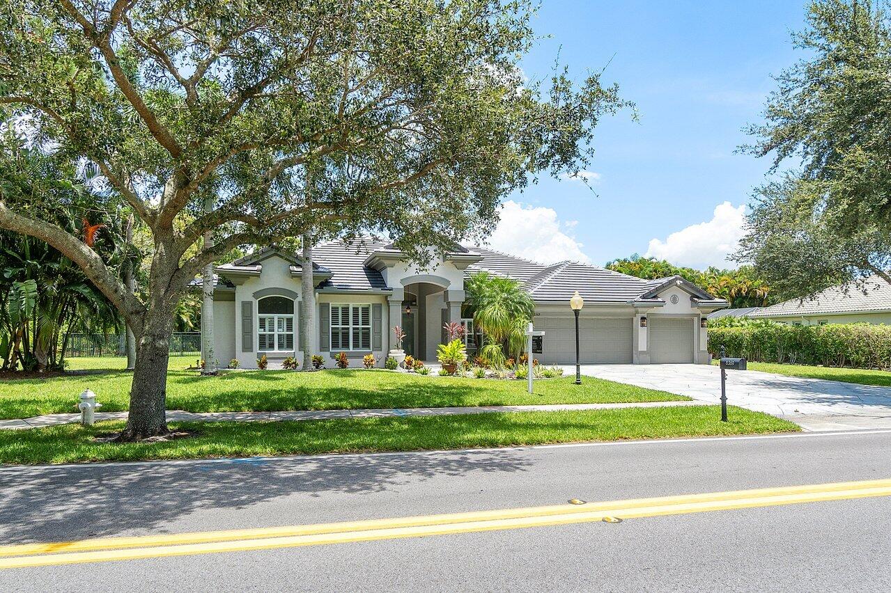 8369 Southeast Island Way Jupiter, FL 33458 - Photo 2 of 41 a front view of a house with a garden and trees