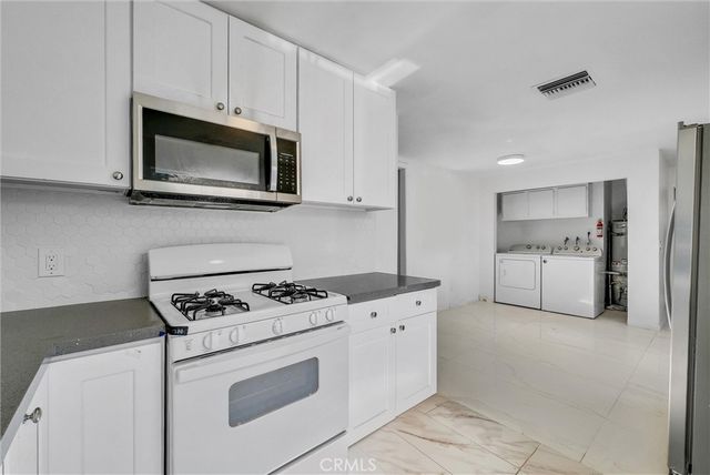 a kitchen with white cabinets and stainless steel appliances
