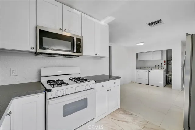 a kitchen with white cabinets and stainless steel appliances