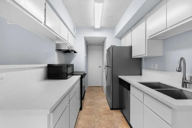 a kitchen with stainless steel appliances a refrigerator a sink a stove and white cabinets