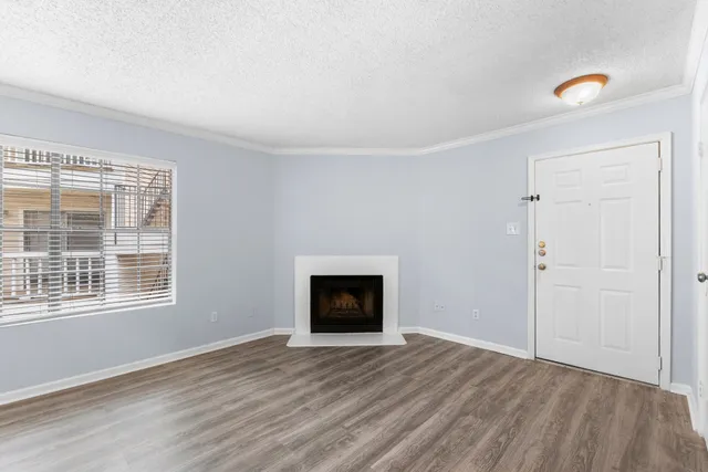 a view of an empty room with wooden floor and windows