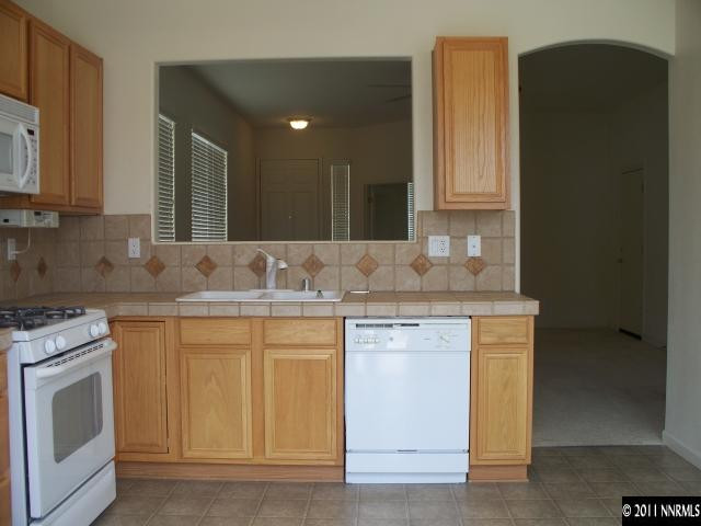 10065 Silver Star Drive Reno, NV 89521 - Photo 4 of 13 a kitchen with granite countertop white cabinets and white appliances