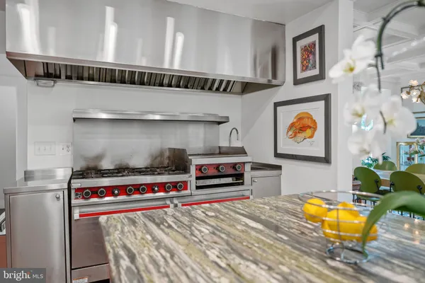 a utility room with stainless steel appliances kitchen island a stove and a wooden floors