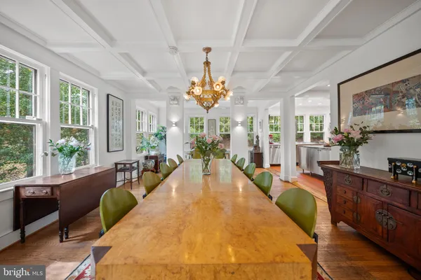 a living room with dining table furniture large windows and wooden floor