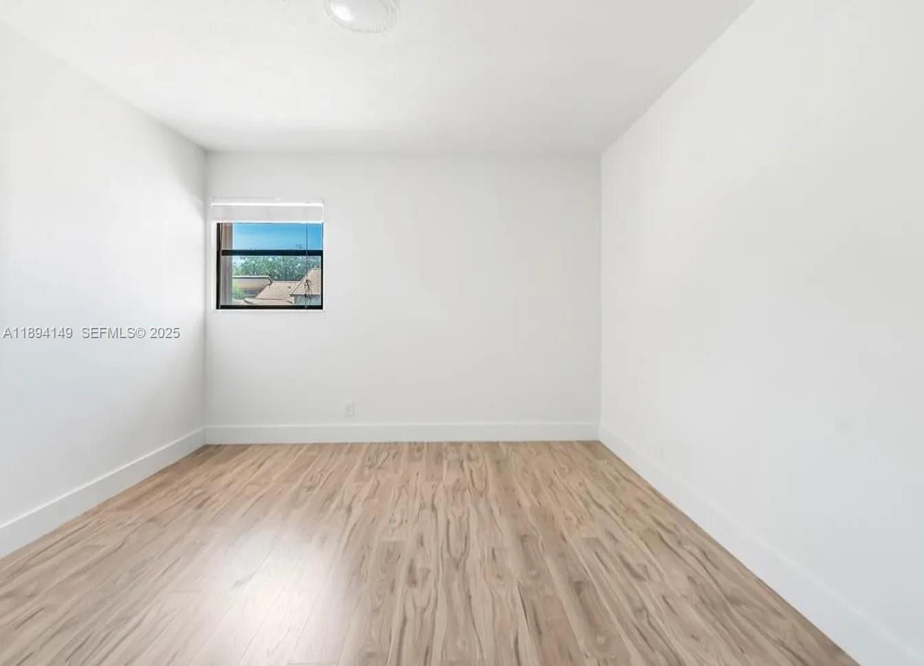 6850 Northwest 2nd Avenue, Unit 34 Boca Raton, FL 33487 - Photo 13 of 23 an empty room with wooden floor and windows