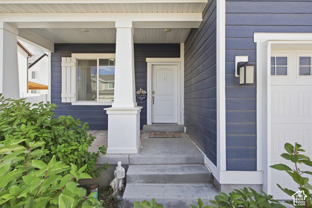 1113 South Raintree Lane Santaquin, UT 84655 - Photo 45 of 59 Covered porch entry featuring white columns, a paneled front door, and a built-in outdoor light fixture
