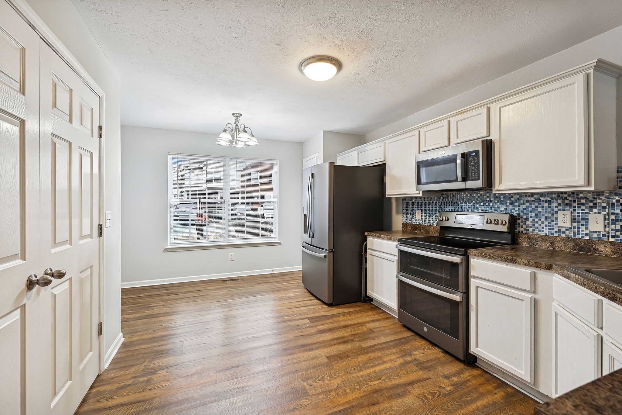 1036 Wolves Den Place Murfreesboro, TN 37128 - Photo 7 of 15 a kitchen with granite countertop a stove a sink dishwasher a refrigerator and a microwave oven with wooden floor