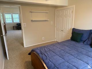 254 Meadow Lane Centerville, UT 84014 - Photo 29 of 34 Carpeted room with a bi-fold door closet, wall-mounted shelving, and a doorway opening to an additional carpeted space with windows