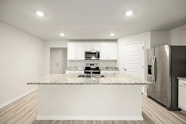 a kitchen with stainless steel appliances granite countertop a refrigerator a stove a sink a microwave and white cabinets