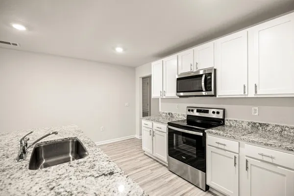 a kitchen with granite countertop a stove a sink and a microwave
