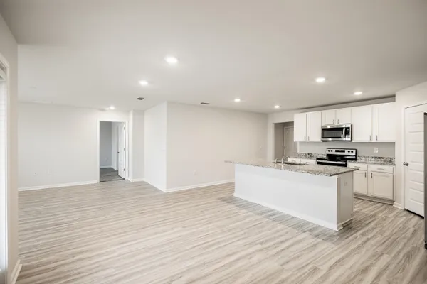 a kitchen with stainless steel appliances kitchen island granite countertop a stove top oven a sink and a refrigerator