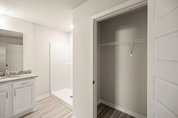 a walk in closet with wooden floor