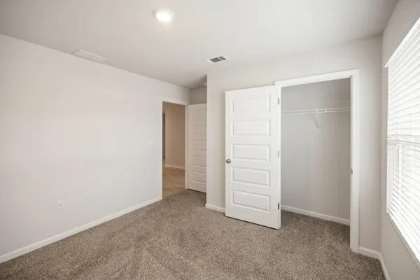 an empty room with closet and windows