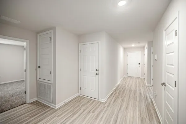 a view of a hallway with wooden floor and a bathroom